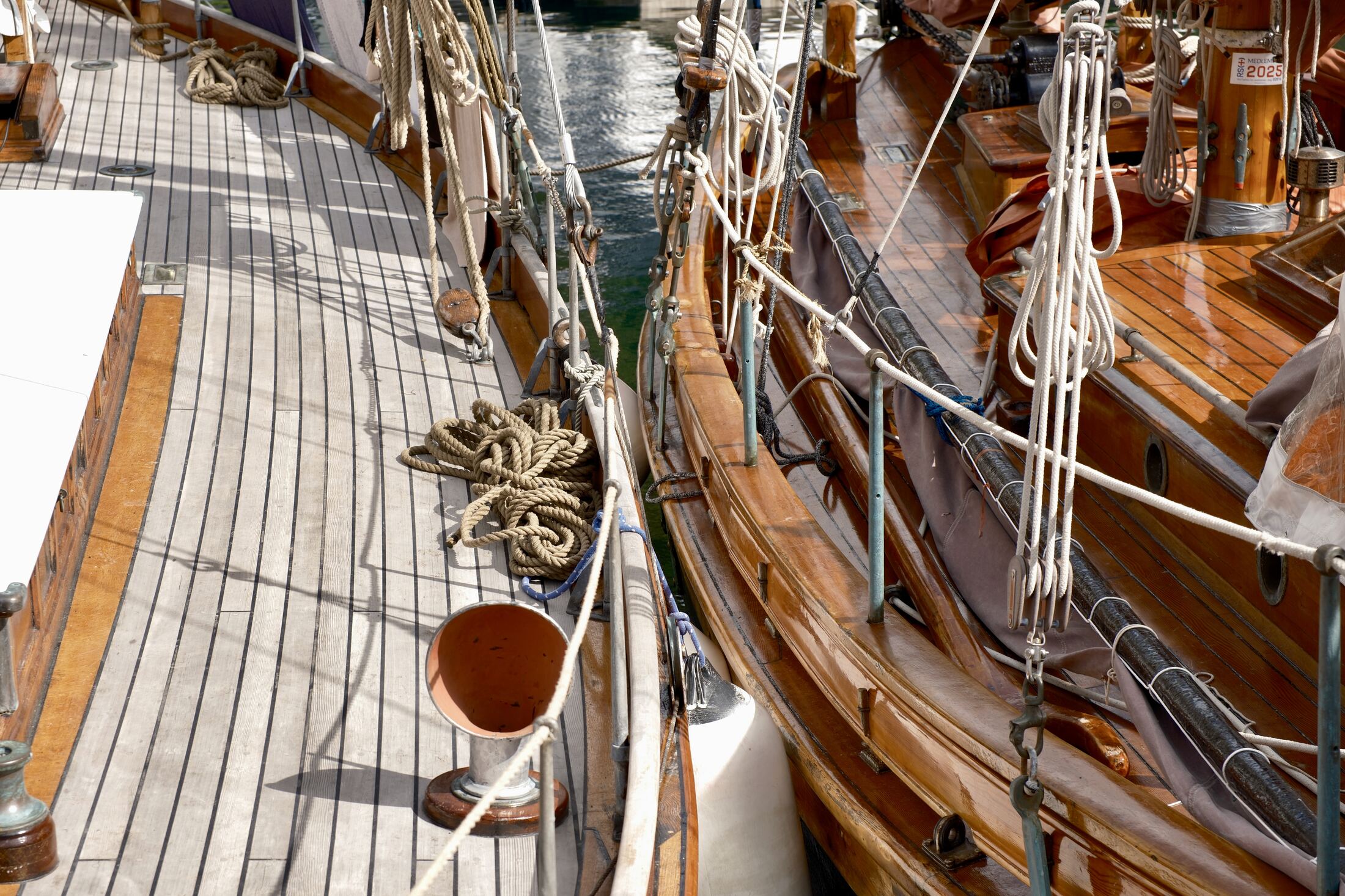 Detail of a teak deck with coiled rope and varnished hull