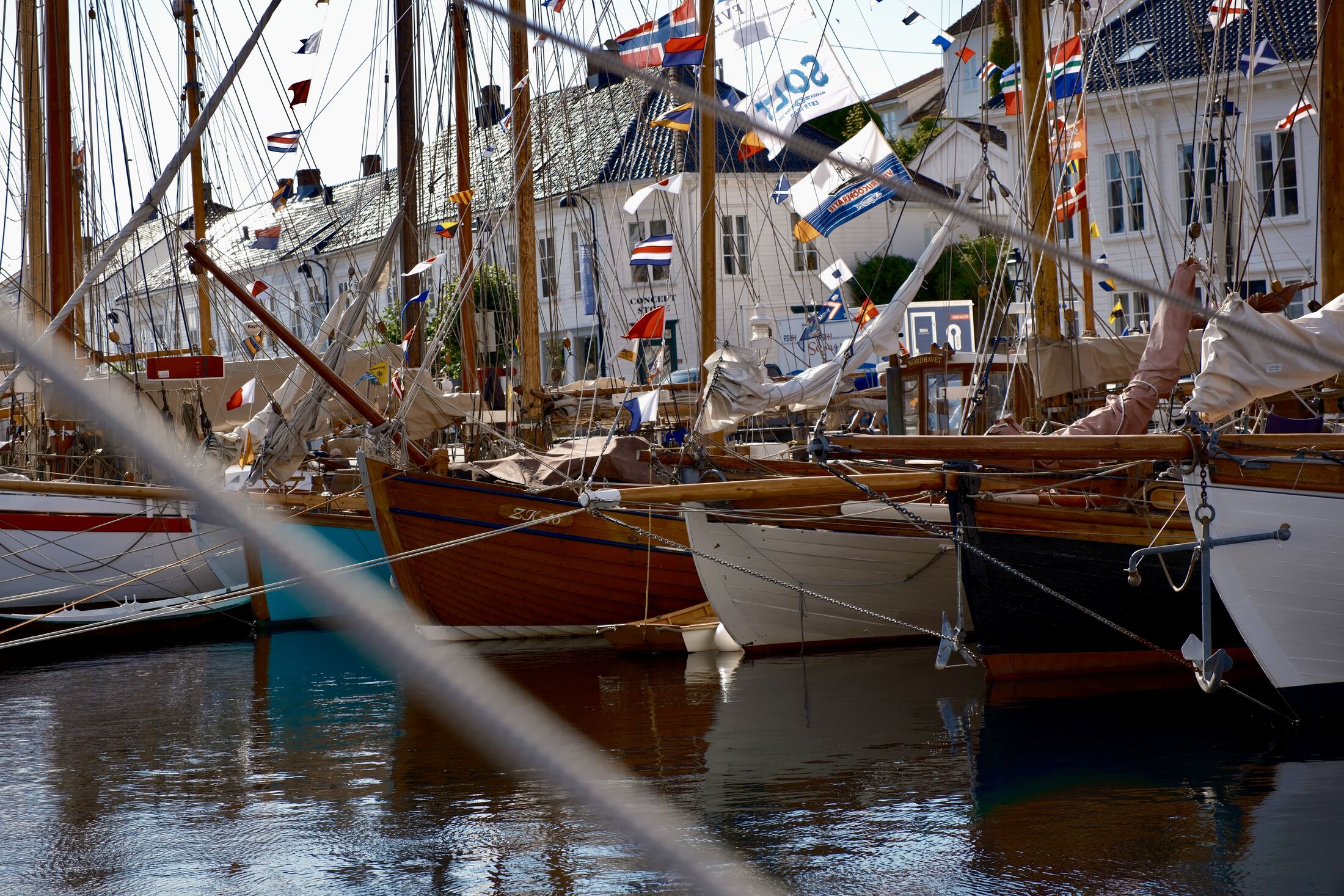 Wooden boats dressed in signal flags before the white houses