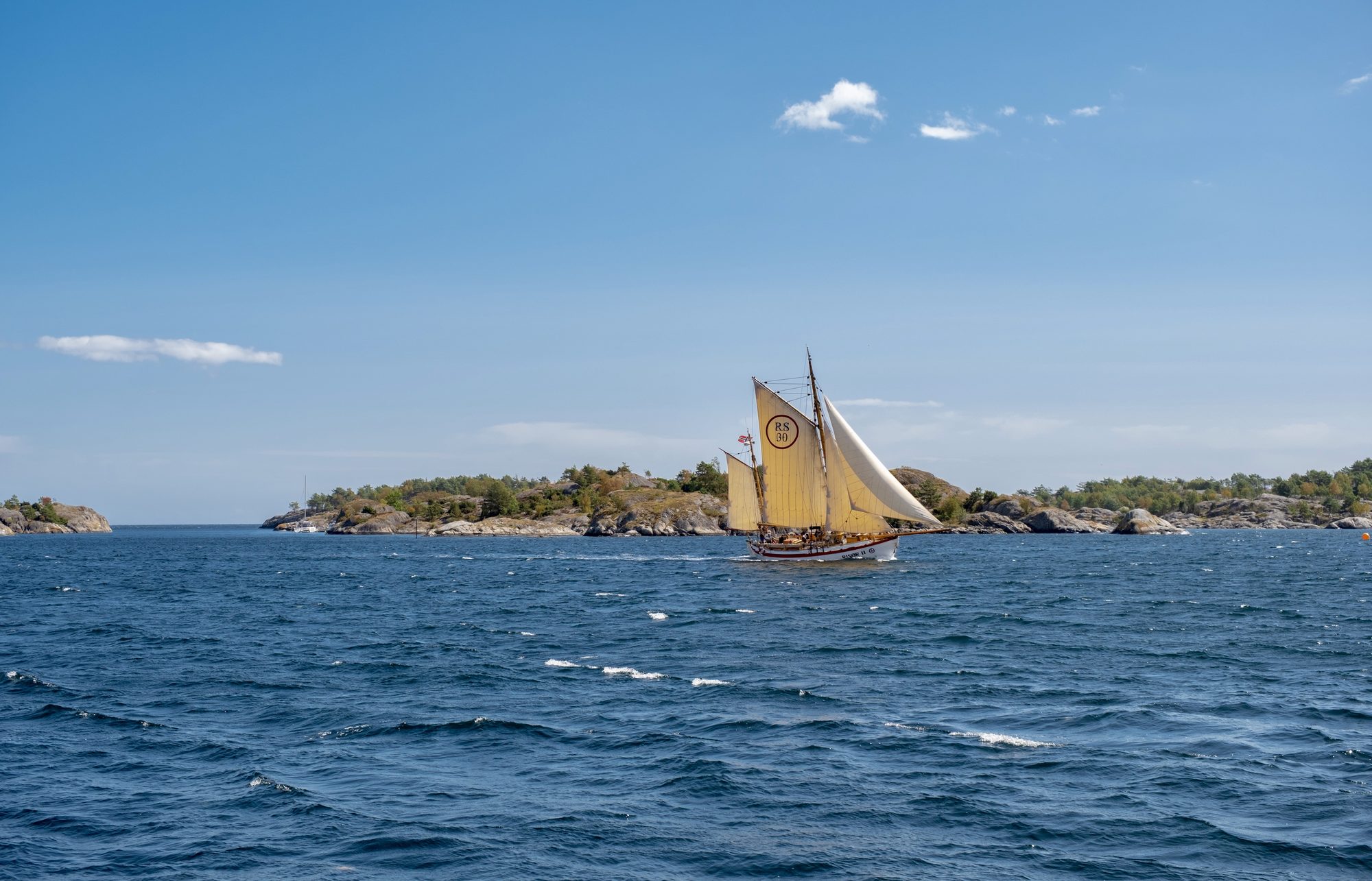 A traditional sailing vessel under full sail in the archipelago